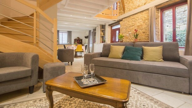 Una sala de estar moderna con un sofá gris, una mesa de centro de madera y una escalera.