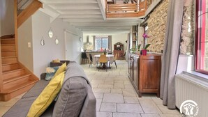 Un amplio salón con escalera de madera, comedor y cocina.