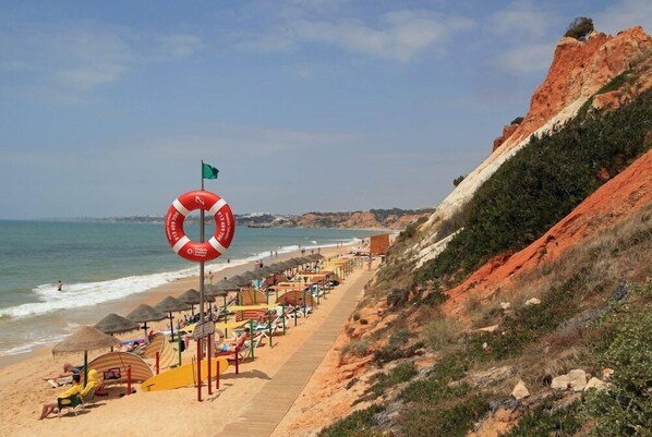 Une plage avec une bouée de sauvetage, des parasols et des chaises de plage.