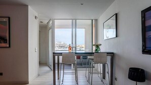 Une cuisine moderne avec une grande fenêtre, deux tabourets de bar et une table à manger.