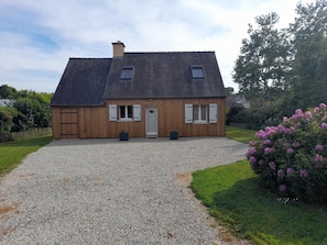 A two-story wooden house with a gravel driveway, a front door, and two windows on the upper floor. - Kerbana - Sarzeau - Gîte (SARZEAU)