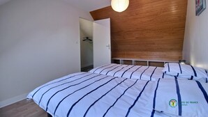 Et soveværelse med sengegavl i træ, seng med stribet sengetøj og en hængende lampe.