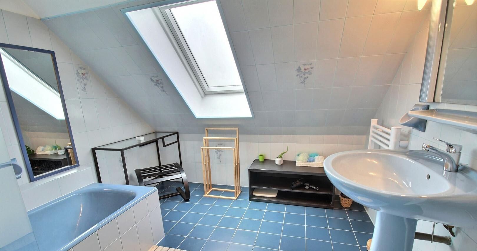 A modern bathroom with a skylight, a bathtub, a sink, and a shower area.