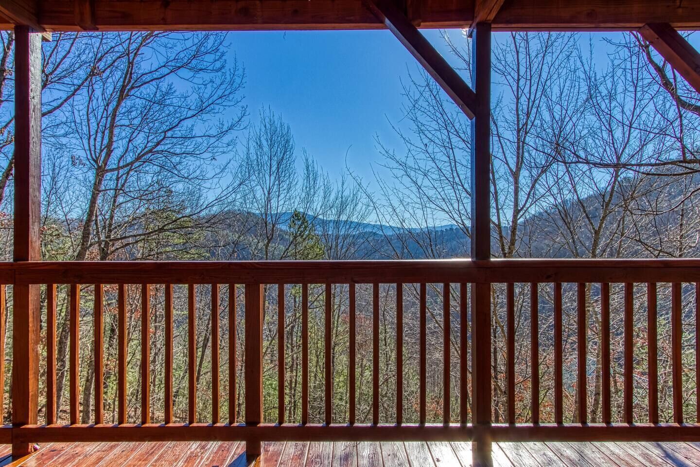 A wooden deck with a view of a forest and mountains.