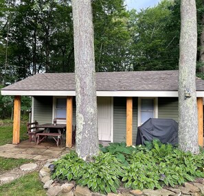 A small cabin with a porch, a table, and chairs. - Bright & Clean Chalet with Hot Tub (Acme)