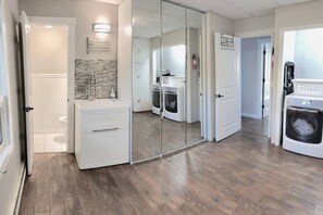 A modern laundry room with a washing machine, dryer, and a large mirror. - Bright & Clean Chalet with Hot Tub (Acme)