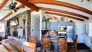 A kitchen with a stone fireplace, wooden beams, and a blue color scheme. - Bright & Clean Chalet with Hot Tub (Acme)