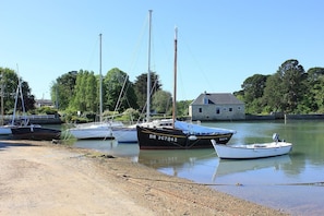 A calm harbor with several boats docked near a stone building.
