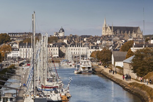 A harbor with boats docked, a cathedral in the background, and a cityscape with buildings.
