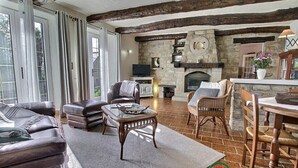 Una sala de estar acogedora con sofás de cuero, una chimenea de piedra y un techo de madera rústica.
