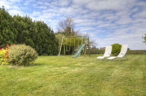 A grassy outdoor area with a swing set, a slide, and two lounge chairs. - De la Quenouille - LOCOAL-MENDON (LOCOAL-MENDON)