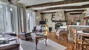 A cozy living room with leather sofas, a stone fireplace, and a rustic wooden ceiling.