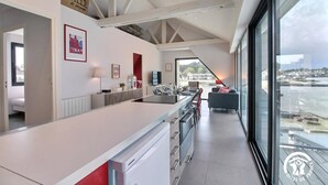 A modern kitchen with a large island, a dining area with a view, and a cozy seating area with a red accent wall.