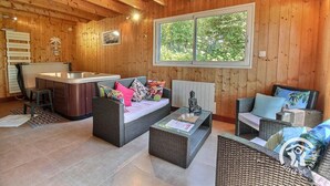 L’intérieur d’un chalet en bois comprend un coin cuisine, deux canapés en osier, une petite table et une grande fenêtre.