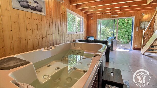 Une cabane en bois avec un jacuzzi, un tableau représentant des pierres et une fleur, et un escalier menant à l’ext érieur.