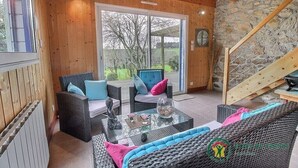 Un intérieur en bois, avec des meubles en osier, une table en verre et un mur en pierre.