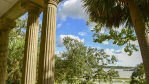 Une vue d’un lac avec un quai, entouré d’arbres et de colonnes.