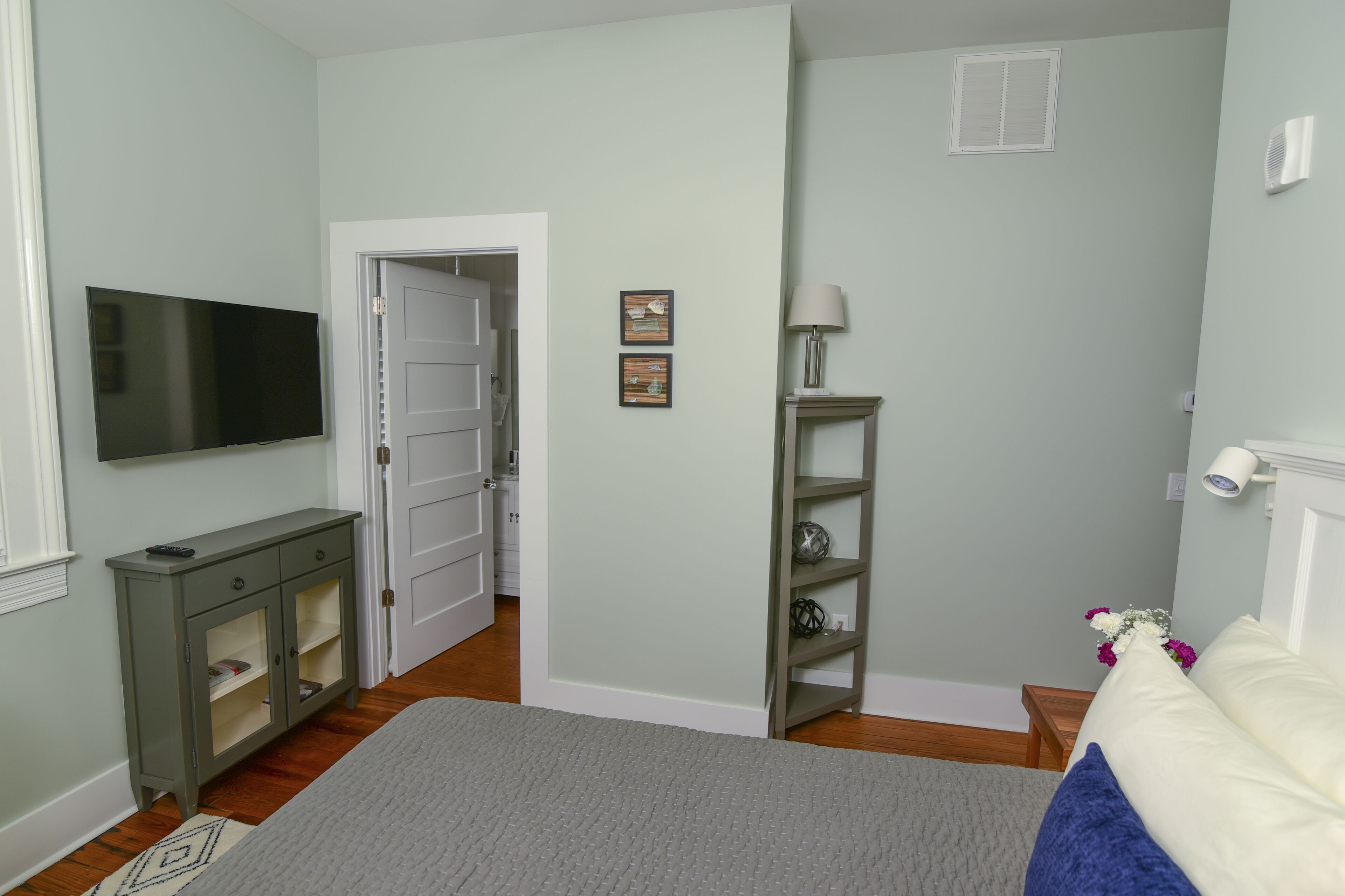 A bedroom with a bed, a television, a cabinet, and a door leading to another room.