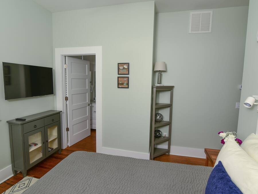 A bedroom with a bed, a television, a cabinet, and a door leading to another room.