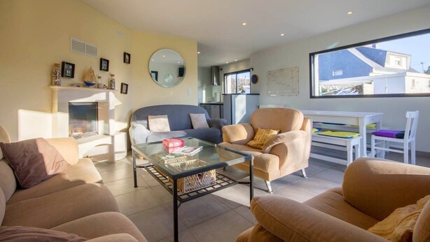 A modern living room with a sofa, armchairs, a glass coffee table, and a dining area with a table and chairs. - Les Filets de la Ria (BELZ)