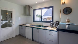 A modern kitchen with a window, a sink, a stove, and a coffee maker. - Les Filets de la Ria (BELZ)