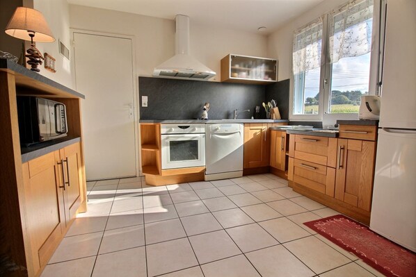 Een moderne keuken met houten kastjes, een inbouwoven en een vaatwasser.