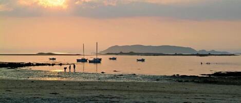 A beach with boats and a distant mountain range.