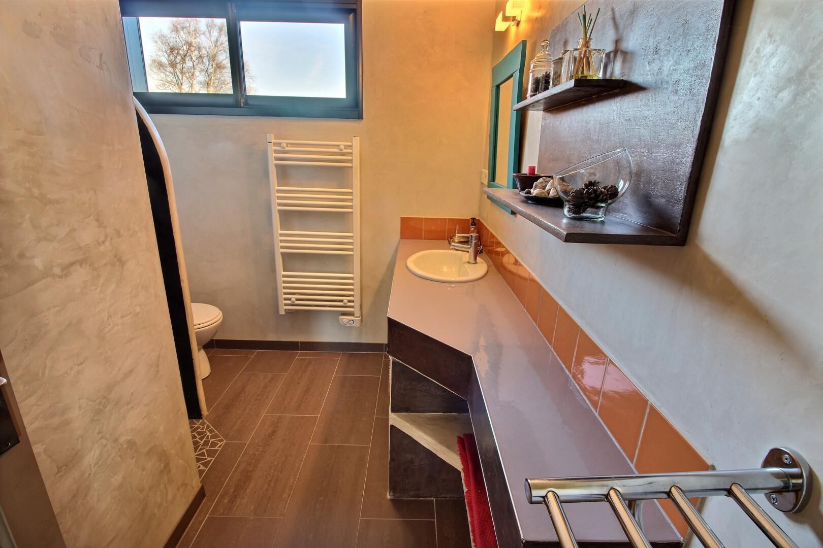 Un baño pequeño con inodoro, toallero, lavabo y estante con artículos de aseo.