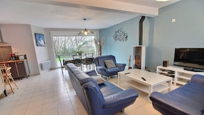 A modern living room with a sofa, armchairs, a coffee table, a TV, and a fireplace.