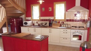 Une cuisine avec un îlot central rouge, des armoires blanches, une cuisinière et un four à micro-ondes.