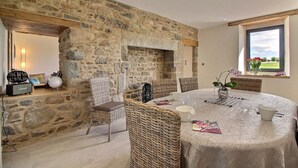 Un coin repas agrémenté d’un mur en pierre, de meubles en osier et d’une table dressée pour quatre personnes.