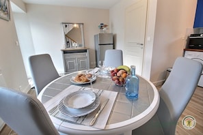 A dining area with a round table set for two, a fruit bowl, and a bottle. - Penty - YVIAS - Gîte (YVIAS)