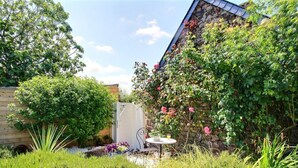 A garden with a table and chairs, a wooden fence, and various plants. - Penty - YVIAS - Gîte (YVIAS)