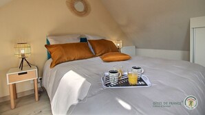 A bedroom with a bed, two nightstands, a tray with two glasses of orange juice, and a logo on the wall. - Penty - YVIAS - G îte (YVIAS)