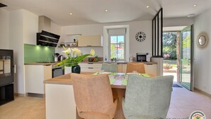A modern kitchen with a dining area, featuring a central island, chairs, and a clock on the wall.