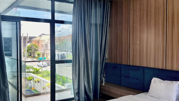 A modern bedroom with a large bed, a view through a glass door, and wooden paneling on the walls. - ATLANTA @ AMERICA LUXURY EXTENDED STAY (Lagos)