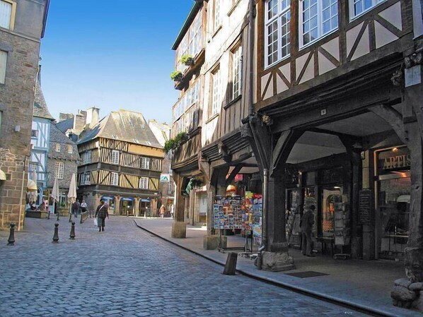 A cobblestone street lined with traditional half-timbered buildings, some with shops on the ground floor.