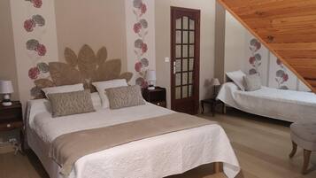 Un dormitorio con dos camas, techo de madera y decoración floral en las paredes.
