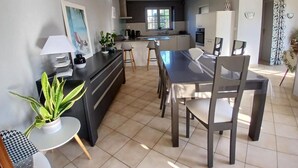 Cocina moderna con comedor, que incluye una isla central, un candelabro y vistas al exterior.