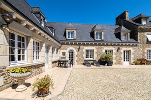 A stone building with a courtyard, outdoor seating, and a flower bed.