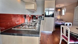 Cocina compacta con estufa a gas, microondas y un refrigerador pequeño.  Cuenta con una zona de comedor con mesa y sillas.