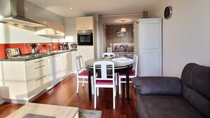 Un espacio habitable compacto con kitchenette, comedor y sofá.