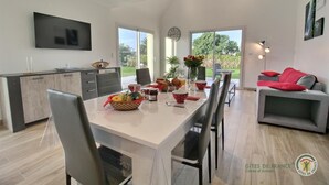 A modern kitchen with a dining area, large windows, and a grey sofa with red cushions. - du Talbert - Pleubian (PLEUBIAN)