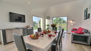 A modern kitchen with a dining area, large windows, and a grey sofa with red cushions. - du Talbert - Pleubian (PLEUBIAN)