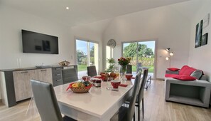 Una cocina moderna con comedor, ventanas amplias y un sofá gris con cojines rojos.