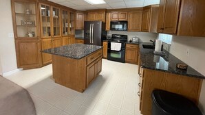 A kitchen with wooden cabinets, a granite countertop, a refrigerator, a microwave, an oven, and a sink. - Spacious and Peaceful (College Place)