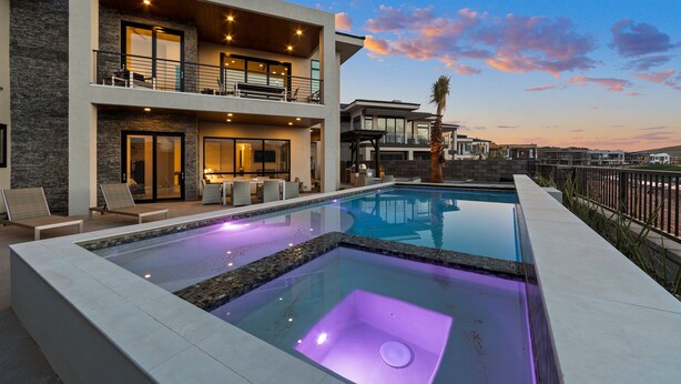 Une maison moderne à deux étages dotée d’une piscine, d’un espace salon extérieur et d’un balcon.