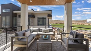 Un espace de vie extérieur moderne, comprenant un ensemble de canapés, une table basse et une vue sur un terrain de golf.