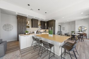 Une cuisine moderne dotée d’un îlot central, de tabourets de bar et d’un coin repas avec une table ronde et des chaises.