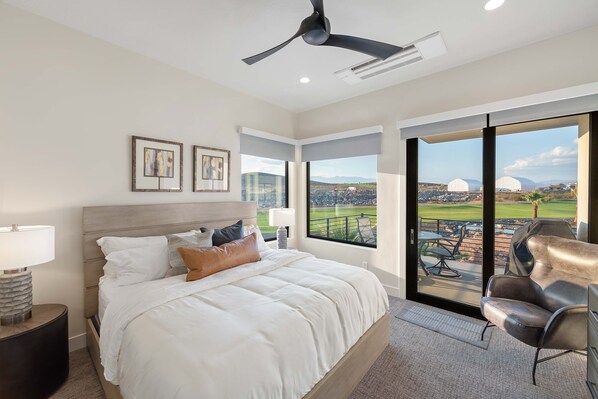 Une chambre dotée d’un grand lit, d’un ventilateur de plafond et offrant une vue sur un terrain de golf par la fenêtre.